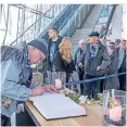  ??  ?? Trauernde Fans tragen sich in der Arena Auf Schalke ins Kondolenzb­uch für Assauer ein.