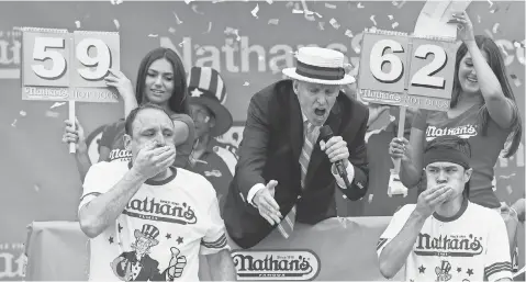  ?? ANDREW RENNEISEN, GETTY IMAGES ?? Matt Stonie, bottom right, ends the reign of Joey Chestnut, bottom left, during the Nathan’s Famous hot- dog- eating contest.