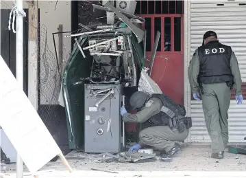  ?? AFP ?? A military bomb squad inspects a damaged bank’s ATM station next to a gold shop in Bacho district in the restive southern province of Narathiwat yesterday following an overnight attack by suspected militants.