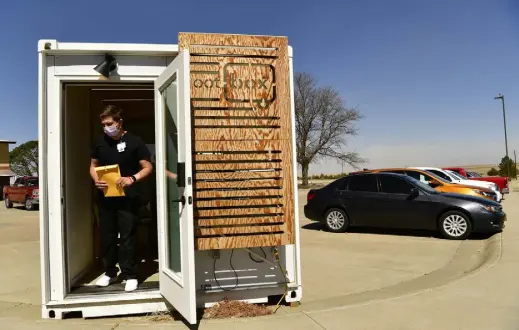  ?? Photos by Helen H. Richardson, The Denver Post ?? Medical assistant Jonah Schofield comes out of the OOT box in the parking lot at Keefe Memorial Hospital on April 4 in Cheyenne Wells. The OOT box is for patients suspected of having COVID- 19. It allows patients to be seen by doctors but remain isolated from the people inside the hospital. The box was purchased with federal pandemic relief money.