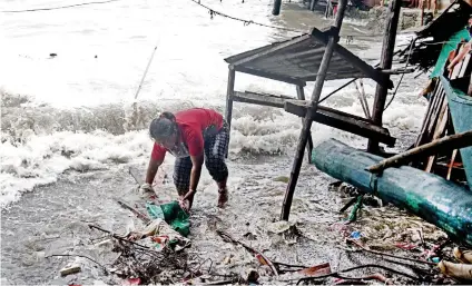  ?? SUNSTAR FOTO / ALEX BADAYOS ?? RUSHING WATER. Florinda Mailda tries to save some materials from her damaged house in Sitio Asan, Barangay Poblacion, Talisay City, Cebu hit by big waves due to a low pressure area.