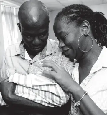  ?? FILE ?? A father, Sinclair Hutton, holding his son, Sae’breon, while mother Suzzett Whyte shows tender love at the Denham Town Police Station in Kingston minutes after the baby was returned to his family by the Child Protection and Family Services Agency. The baby had been stolen from the Victoria Jubilee Hospital.
