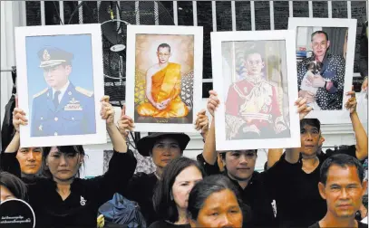  ?? Sakchai Lalit ?? The Associated Press Mourners hold up portraits of the late King Bhumibol Adulyadej near Grand Palace to take part in the Royal Cremation ceremony Wednesday in Bangkok, Thailand. Bhumibol will be honored in a royal cremation ceremony from Oct. 25 to 29.