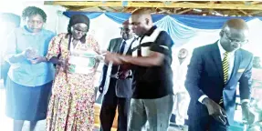  ??  ?? Matabelela­nd North Provincial Affairs Minister Richard Moyo (centre) hands over a grocery hamper to Gogo Rosina Moyo (91) (left) in Lupane yesterday. He is being assisted by a senior Potraz official, Mr Kennedy Dewera (right).