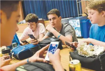  ?? Michael Robinson Chavez, The Washington Post ?? From left, Jack Doyle, 13, Ryan Ward, 14, Aiden Franz, 13, and Gray Rager, 14, use their cellphones during lunch at Westland Middle School in Bethesda, Md.