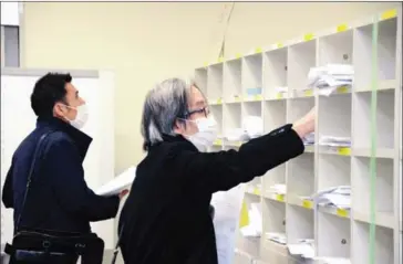  ?? THE YOMIURI SHIMBUN ?? Company employees put financial statements in cubby holes at the Tokyo Stock Exchange on Friday. The number of such employees was fewer than usual under the state of emergency.