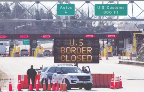  ?? LARS HAGBERG / AFP ?? U.S. Customs officers stand by a sign this week announcing that the border is closed at Lansdowne, Ont. Reports that the White House is seeking to send soldiers to the northern border have sparked exasperati­on from Canadian officials.