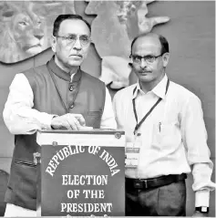  ??  ?? Vijay Rupani (left), Chief Minister of the western state of Gujarat, casts his vote during presidenti­al election in Gandhinaga­r. — Reuters photo