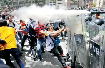  ??  ?? Manifestan­tes se enfrentan a las fuerzas de seguridad durante un mitin, ayer, en rechazo del gobierno de Nicolás Maduro, en Caracas. La oposición afirmó que hubo 9 heridos, incluyendo uno de bala.