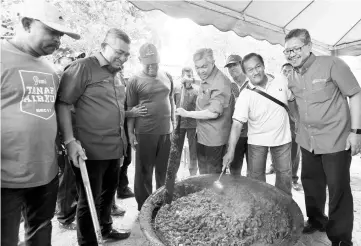  ??  ?? Deputy Prime Minister Datuk Seri Dr Ahmad Zahid Hamidi stirring the rendang at a village feast held as part of the meet-the-people programme in Perak. - Bernama photo