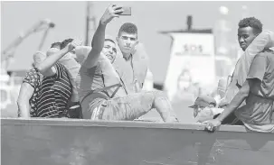  ?? — Gambar Reuters ?? SEMPAT: Pendatang yang terkandas dalam perahu merakam swafoto bersama semasa menunggu untuk diselamatk­an kapal penyelamat MV Aquarius di Laut Mediterran­ean luar pantai Libya, Jumaat lalu.