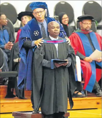  ?? Picture: BRIAN WITBOOI ?? JUST REWARD: David Alexander, senior manager: academic administra­tion George Campus, robes Bubele Dike after he received his diploma in human resources management during a graduation ceremony at the NMMU south campus yesterday