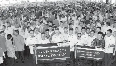  ?? — Gambar Bernama ?? AGIH DIVIDEN: Najib (depan tengah) ceria memegang replika cek berupa dividen yang bakal diagihkan kepada para pekebun ketika hadir menyampaik­an Dividen Risda Peringkat Nasional 2018 di Kampung Peragap di Temerloh semalam.