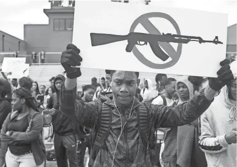  ??  ?? Kyus Carter, a junior at Cordova High School, holds up a sign during a student walkout at Cordova High School in Memphis to protest gun violence. BRAD VEST/THE COMMERCIAL APPEAL