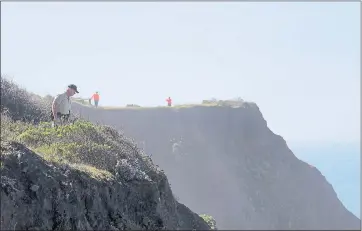  ?? THE ASSOCIATED PRESS ?? Deputy Bill Holcomb, left, and search and rescue volunteers view in March an area near Mendocino where Jennifer Hart drove her wife and six adopted children off a cliff into the Pacific Ocean.