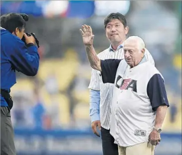  ??  ?? FORMER DODGERS manager Tommy Lasorda waves to spectators at Dodger Stadium as Hideo Nomo, a former standout pitcher in Japan and with the Dodgers, waits to throw the ceremonial first pitch.