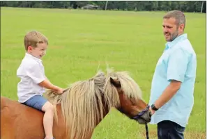  ??  ?? Noah Nelson, 4, rides his pony, Bo, as Chris Nelson guides them near the fence on the family’s property in Malvern. The Nelsons were recently named the 2019 Hot Spring County Farm Family of the Year.