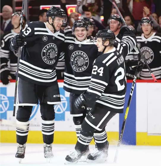  ?? JONATHAN DANIEL/GETTY IMAGES ?? Alex DeBrincat (center) celebrates his hat trick against the Senators with Carl Dahlstrom (left) and Dominik Kahun at the United Center on Monday.