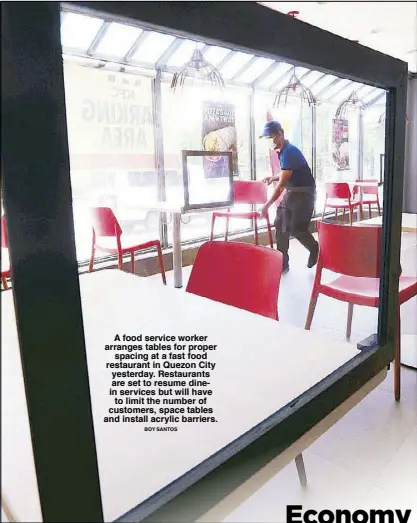  ?? BOY SANTOS ?? A food service worker arranges tables for proper spacing at a fast food restaurant in Quezon City yesterday. Restaurant­s are set to resume dinein services but will have to limit the number of customers, space tables and install acrylic barriers.