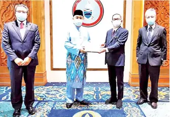  ??  ?? Hajiji presenting a souvenir to Maximus during the courtesy call, while Zulkapli (left) and Petrus (right) look on.