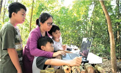  ??  ?? Esther helping her children, Joshua (left), Jordon and Joshen (right) to follow teaching and learning at home on a hill at Kampung Gana, Papar.