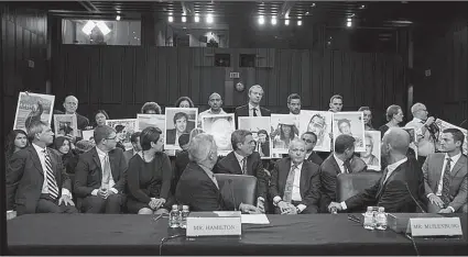  ?? -AP ?? John Hamilton, VP of Boeing Commercial Airplanes, and Boeing CEO Dennis Muilenburg look back at family members holding photograph­s of Boeing 737 MAX crash victims as Hamilton and Muilenburg testify before a Senate.