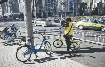  ?? SHEN QILAI / BLOOMBERG ?? An employee of Ofo Inc, a bike-sharing company, takes pictures of parked Bluegogo bikes in downtown Beijing. The proliferat­ion of bikesharin­g in the country has fuelled a new round of cash-guzzling competitio­n. With newcomers joining in the fray, most...