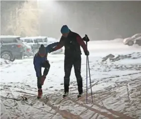  ?? MICHAEL SEARS / MILWAUKEE JOURNAL SENTINEL ?? Tom Cousland of the Town of Delafield (right) helps his daughter, Sammi, 11, get her skis on as the pair prepared to head out onto the lighted cross country ski trail at the Kettle Moraine State Forest, Lapham Peak Unit, near Delafield. Photo gallery...