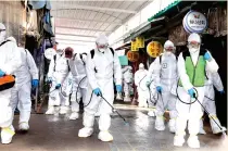  ?? AP ?? Workers wearing protective suits spray disinfecta­nt as a precaution against the coronaviru­s at a market in Bupyeong, South Korea. —