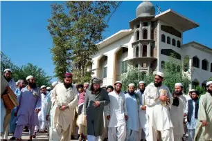  ?? —AP file ?? Maulana Samiul Haq (centre in grey turban) is surrounded by students as he leaves after delivering a lecture at his seminary in Akora Khatak.