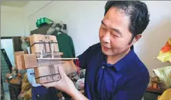  ?? ZOU XIAOHUA / FOR CHINA DAILY ?? Xiong Wenyi displays one of the wooden locks he has collected over the past 30 years in his storeroom in Jiangxi province.