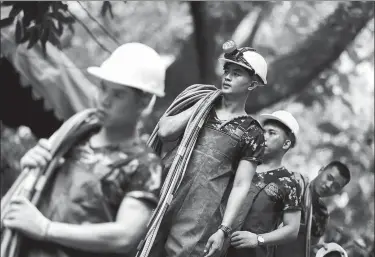  ?? ATHIT PERAWONGME­THA / REUTERS ?? Military personnel carry diving cables out of the Tham Luang cave complex, where members of an under-16 soccer team and their coach were found alive after 10 days undergroun­d, in Chiang Rai, Thailand, on Thursday.