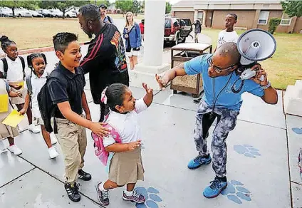  ?? [PHOTO BY PAUL HELLSTERN, THE OKLAHOMAN] ?? Volunteer Ernest Odunze gives high-fives to children at the beginning of the first day of school Tuesday at Thelma Parks Elementary School in Oklahoma City.