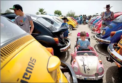  ?? AP/ODED BALILTY ?? A child sits in a toy Volkswagen Beetle during a gathering Friday of devotees of the vehicle in Yakum, Israel. In the United States, Volkswagen is trying to put the scandal over emissions cheating behind it.