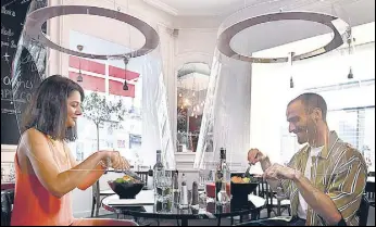  ?? AFP ?? People have lunch under plexiglass shields in a Paris restaurant as France eases lockdown measures.