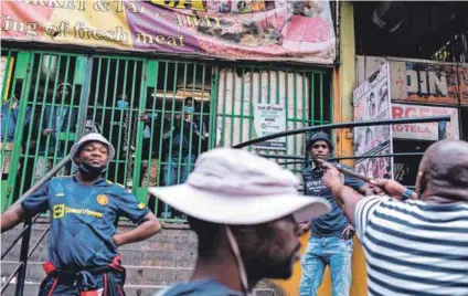  ?? Photo:emmanuel Croset/afp ?? Criminal: An Operation Dudula member aims a ‘firearm’ at onlookers in Hillbrow during the vigalante movement’s raid on Africans from other countries.