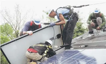  ??  ?? Workers put solar panels down during an installati­on in Washington, DC. — Reuters photo