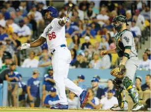  ??  ?? LOS ANGELES DODGERS slugger Yasiel Puig (left) watches the trajectory of his two-run home run in the fourth inning of the Dodgers’ 10-7 home victory over the Oakland Athletics on Wednesday night.