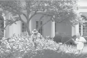  ?? ANDREW HARNIK/AP ?? About 4 million federal workers are to be vaccinated by Nov. 22 under the president’s order aimed at stopping the spread of the coronaviru­s. Above, the Oval Office is visible behind a U.S. Park Service worker watering the Rose Garden.