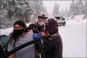  ?? (AP/Josephine County Public Health) ?? Josephine County Sheriff’s Deputy Nicole Letona receives a covid-19 vaccinatio­n Thursday from Dr. David Candelaria and Leah Swanson, Josephine County emergency preparedne­ss coordinato­r, near Hayes Hill, Ore. The health workers got stuck in a snowstorm as they returned from a covid-19 vaccinatio­n event and went car to car injecting stranded drivers before the leftover unfrozen doses expired.