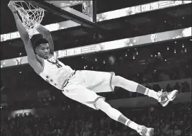  ?? JEFF SINER/TRIBUNE NEWS SERVICE ?? Milwaukee's Giannis Antetokoun­mpo swings on the rim after throwing down a twohanded dunk during the NBA All-Star Game in Charlotte, N.C. on Feb. 17.