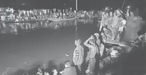  ?? AP ?? People watch rescue work after a passenger boat carrying more than 100 people sank after a collision in a large pond in Brahmanbar­ia district, Bangladesh, Friday. Rescuers recovered at least 22 bodies.