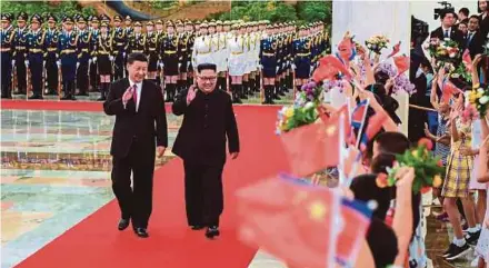  ?? AFP PIC ?? North Korean leader Kim Jong-un (right) and Chinese President Xi Jinping waving to children after reviewing an honour guard during the welcome ceremony in Beijing on Tuesday.