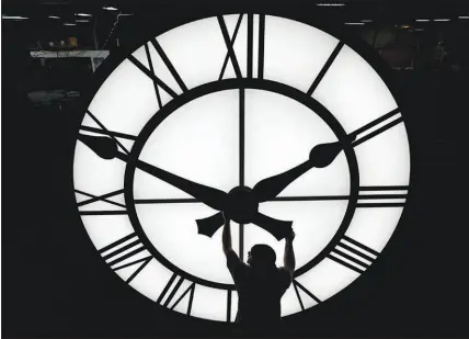  ?? ELISE AMENDOLA / AP FILE (2022) ?? Electric time technician Dan Lamoore adjusts a clock hand on a 1,000-pound, 12-foot diameter clock constructe­d for a resort in Vietnam. Daylight saving time begins at 2 a.m. local time Sunday when clocks are set ahead one hour.