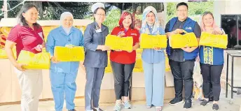  ?? ?? Fatimah (third right), Rotary Internatio­nal 3310 district governor Joanne Kam (centre) and others show packs of reusable diapers for distributi­on under the Rotary Pan Borneo Joint Club Project.