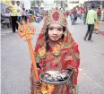  ??  ?? A girl dressed as an Indian goddess attracts tourists at the main market.