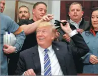  ?? LEAH MILLIS / REUTERS ?? US President Donald Trump hands out pens he used to sign proclamati­ons placing tariffs on steel and aluminum imports to workers from the steel and aluminum industries at the White House on Thursday.