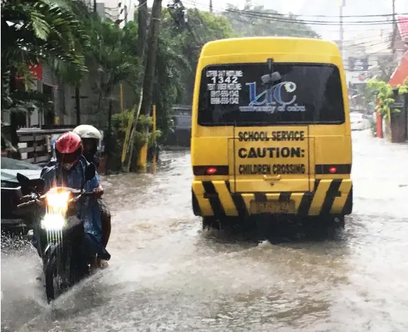  ?? PAUL JUN E. ROSAROSO ?? A school bus passes through a flooded portion of Jakosalem Street in Cebu City during a downpour yesterday afternoon.