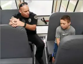  ?? PETE BANNAN — DIGITAL FIRST MEDIA ?? Mary C. Howse Elementary student Ryan Schellhamm­er speaks with West Whiteland Police Detective Jeff McCloskey, who rode the school bus Wednesday to speak to the children about school bus safety as part of Operation “Safe Stop.”