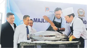  ??  ?? Ahmad Shabery cutting a tuna as a symbolic launch of the landing of tuna from Malaysian cargo ship Kha Yang 333 to the Deep Water Wharf in Butterwort­h yesterday. At second left is Penang Port Commission secretary Datuk Tan Teik Cheng. — Bernama photo